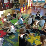 Dzieci siedzą wokół obręczy z dużymi guzikami w środku.