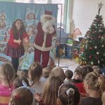 Naprzeciwko dzieci stoi kobieta i osoba w ubraniu Mikołaja.