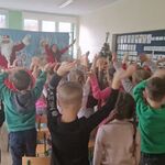 Dzieci i dwoje aktorów stoją_ machając rękami w górze.