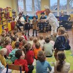 Dwóch chłopców stoi przy muzykach trzymając instrumenty w rękach.
