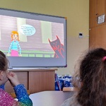 Dwie dziewczynki siedzą przy stoliku_ na ekranie wyświetklony film.