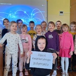 Dzieci stoją na tle ekranu_ chłopiec trzyma kartkę z napisem.jpg
