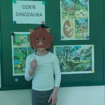 Dziewczynka przykłada do głowy maskę triceratopsa.
