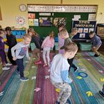 Na dywanie leżą krążki i ślady dinozaura_ dzieci poruszają się zgodnie z poleceniami.