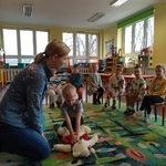 Chłopiec w obecności kolegów ćwiczy na misiu masaż serca.
