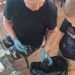 pani siedzi na krzesełku_ obok worek z ziemią_ chłopiec małą łopatką sypie ziemię.