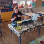 pani siedzi przy stoliku na którym leżą doniczki z ziemią.