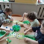 Kilkoro dzieci przy stoliku wykonuje pracę plasyczną.