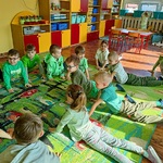 Dzieci leżąc na podłodze unoszą tułów w oparciu o ręce.