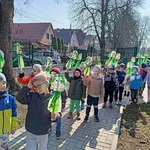 Przedszkolaki idą chodnikiem trzymają sylwetki pani Wiosny.