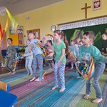 Dzieci stoją w rzędach ze wstążkami w rękach naśladują ruchy taneczne