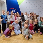 grupa dzieci pozuje na tle ścianki w zakładzie PGE.