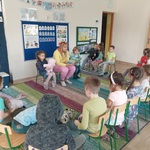 Dzieci oraz Pani siedzą w kółku_ Pani siedzi na środku_ czyta książkę.