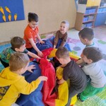 uśmiechnięci chłopcy owijają dziewczynki chustą animacyjną.