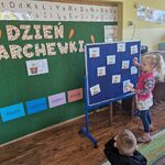 Dziewczynka stoi przed tablicą i dopasowuje odpowiedni fragment marchewki.