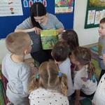 Dzieci są blisko Pani, która czyta, zaglądają do książki 