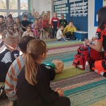  Pani ratownik  pochylona nad torba medyczna omawia zawartość torby, dzieci słuchają 