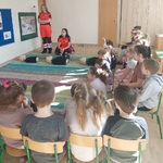  Dzieci siedzą na krzesłach, zwrócone twarzą do ratowników 