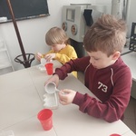  Dwaj chłopcy wlewają odlew gipsowy do foremek.