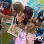 gromadka dzieci pochylona nad wydrukowanymi obrazkami.