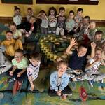 dzieci siedzą na dywanie dookoła serca ułożonego z książek.