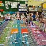 Dwoje dzieci układa na dywanie obrazki z kilku elementów w całość.