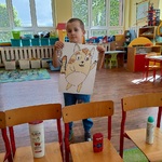 Chłopiec stoi za krzesełkiem_ na którym leży dezodorant i trzyma sylwetę kota Pupika.