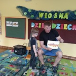 Mężczyzna siedzi na krześle obok chłopca i pokazuje obrazek z rybą.