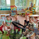 Dzieci przyglądają się koledze trzymającemu podbierak do ryb.
