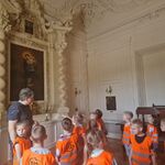 Grupa dzieci i przewodnik znajdują się w pałacowej kaplicy.