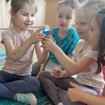 Czworo dzieci oglądają z zaciekawieniem klepsydrę.