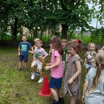 Dzieci podzielone na zespoły przygotowują się do biegu sztafetowego.