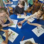 5 Dzieci siedzą przy stolikach i kolorują obrazki przedstawiające bajkę o Muminkach.jpg
