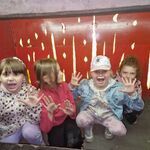 Cztery dziewczynki robiące groźne miny siedzą w stylizowanym piecu.