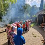 Grupa dzieci stoi naprzeciwko pana trzymającego otwartą książkę.