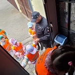 kilkoro dzieci wchodzi do furgonetki_ funkcjonariusz pomaga wejść na schody.
