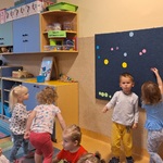 Dwoje  stoi przy tablicy_ dziewczynka trzyma kropkę dwie dziewczynki idą w kierunku tablicy.
