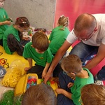 Mężczyzna pokazuje dzieciom sposób wykonania konstrukcji z klocków.