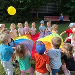 dzieci na podwórku odbijają balon przy pomocy kolorowej chusty.