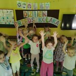 grupa uśmiechniętych dzieci z rękami podniesionymi do góry.