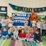 Grupa dzieci pozuje z mężczyzną trzymającym książkę.