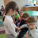 Dziewczynka rozdaje dzieciom naklejki.