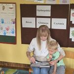 Na krzesełkach przy tablicy siedzi kobieta ze swoim synkiem.