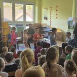 Grupa dzieci z instrumentami w rękach maszeruje za muzykiem.
