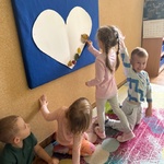 Dziewczynka przykleja listek na serduszko.