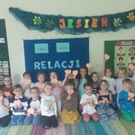 Wszystkie dzieci z grupy siedzą pod tablicą, trzymają w rękach zrobione przez siebie serca 