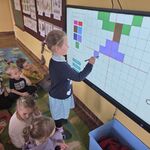 Dziewczynka tworzy obraz na tablicy multimedialnej wg kodu.