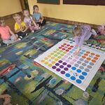 Na dywanie leży mata_ dziewczynka układa obrazki z owocami wg kodu.