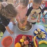 Troje dzieci próbuje zanurzyć w misce wody częściowo obraną cytrynę.
