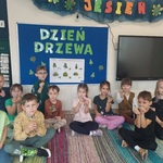Grupa dzieci siedzi pod tablicą z napisem 